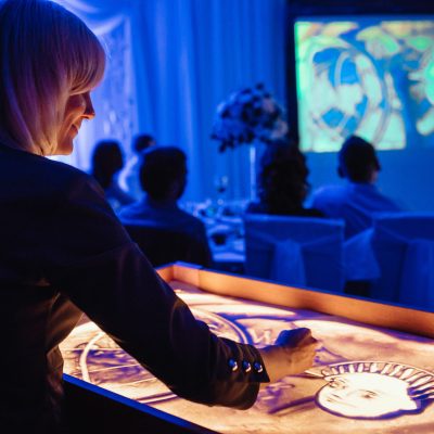the artist paints plot paintings with sand on a lighted table